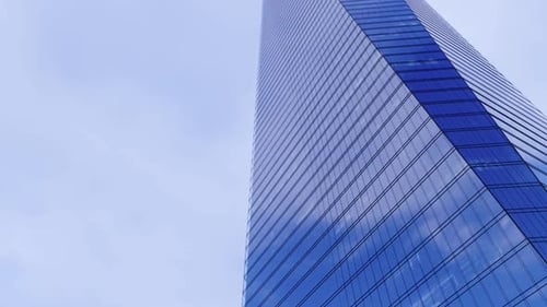 Blauer Himmel und weiße Wolken, die sich in einem Glasgebäude spiegeln Zeitraffer