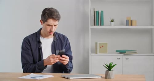 Man Using Smartphone at Desk Indoors