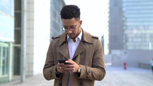 Young Adult Using Smartphone on City Street