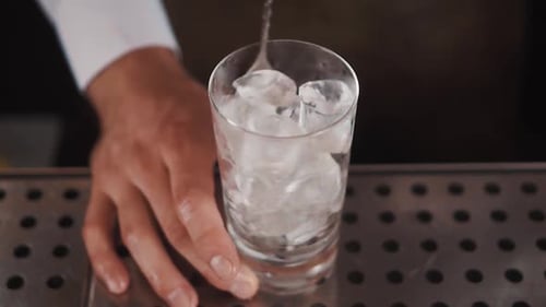 Bartender Adds Liquid to Glass with Ice