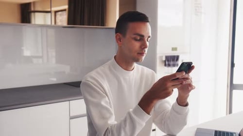 Professional Creative Man Sitting at His Desk in Home Office Studio Using Smartphone, Man Using