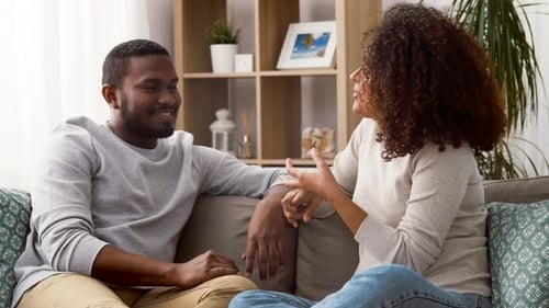 Happy Couple Sitting on Sofa and Talking at Home