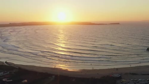 Luftaufnahme des Sonnenuntergangs an der Küste mit Surfern im Hintergrund