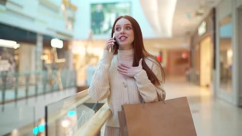 Woman Talks on Phone With Shopping Bags in Mall