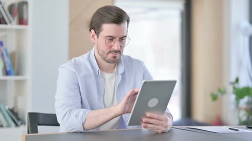 Attractive Man in Glasses Using Tablet in Office
