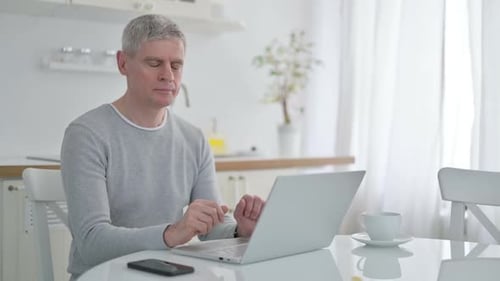 Man Working on Laptop and Smiling at Camera