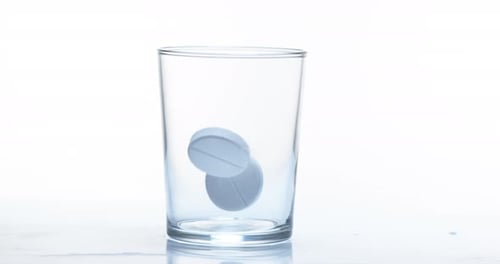 900060 Tablets, die vor weißem Hintergrund in ein Glas fallen, Zeitlupe 4K