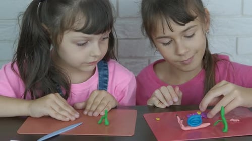 Girls Making Clay Figures at Table Indoors