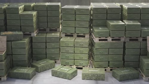 Huge stack of ammo boxes with RPG missiles and rifle ammunition in warehouse.