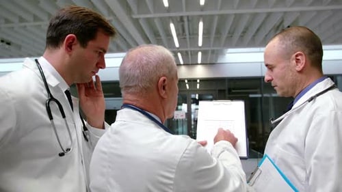Three Doctors Discussing Document in Hospital