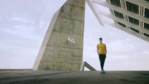 Young Man on Skateboard Stands near Modern Building