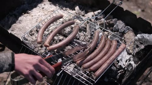 Nahaufnahme von leckeren Würsten beim Grillen auf Holzkohlegrillrost