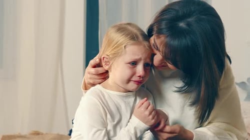 Mama beruhigt ihre kleine Tochter, die viel weint