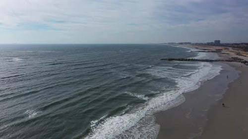 A drone view over an quiet beach with a few people walking in the morning. The camera dolly in and p