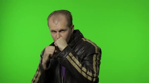 Man Wearing Leather Jacket Boxing Against Green Background