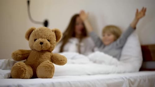 Teddy Bear Focus with Adult and Child in Bed