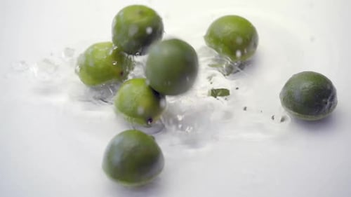 SLOMO von Limes fällt ins Wasser auf weißem Hintergrund
