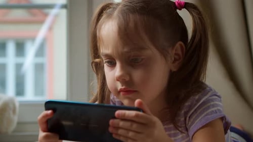 Child Focused on Smartphone Device Indoors by Window