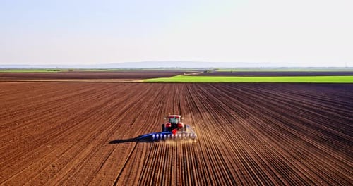 Farmer in tractor seeding corn on agricultural field
