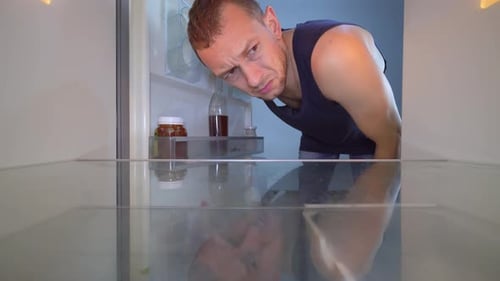 Man Looks Inside Near Empty Refrigerator