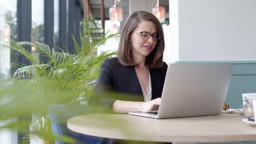Happy Young Businesswoman Using Laptop Computer in a Cafe