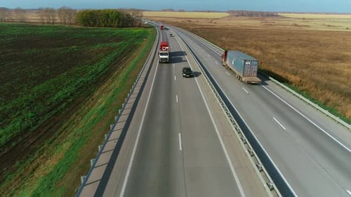 Trucks and Cars Drive Along the Highway
