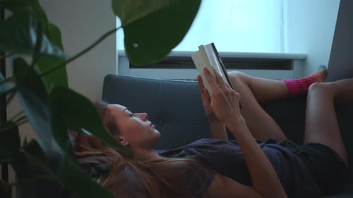 Woman Reading Book on Couch at Home