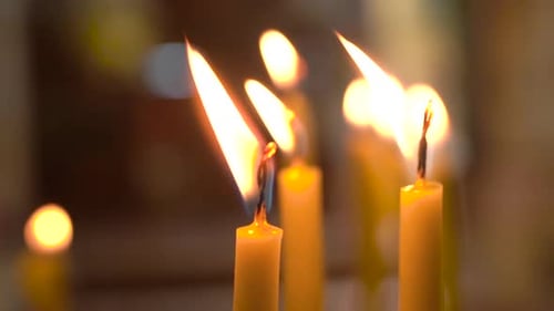 Extreme Close Up Shot of Candles Burning And Flame Waving Inside of Church