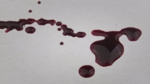 Dark Red Liquid Drops and Pools on White Surface