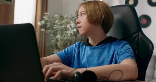 A Young Boy Taps Fingers on the Keyboard of a Laptop