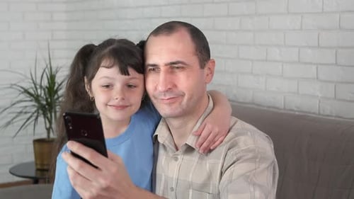 Smiling Father and Child Using Mobile Phone Indoors