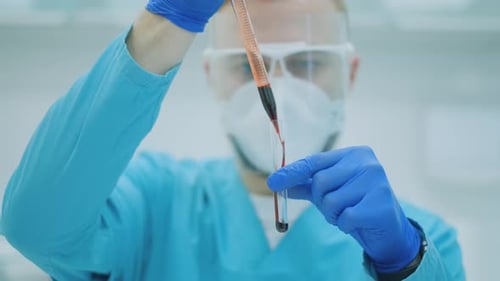 Technician Carefully Adding Blood Sample to Test Tube