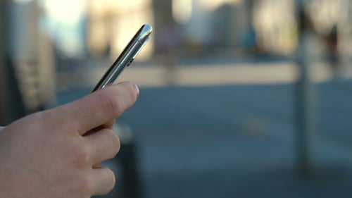Manos de hombre hipster usando su teléfono inteligente al aire libre en el parque.