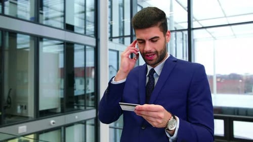 Man in Suit Talks on Phone, Holds Credit Card