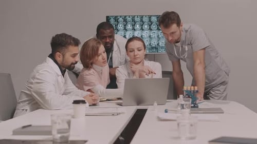 Medical Team Collaborating on Laptop in Modern Office