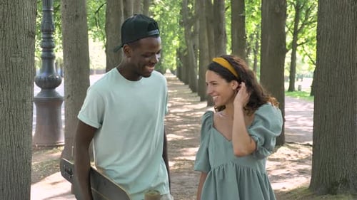 Couple Strolling and Talking in Tree-lined Park