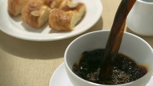 Pouring Coffee with Almond Croissants on Table