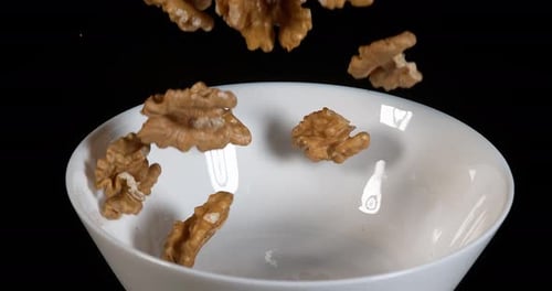 Walnuts Falling into a White Bowl
