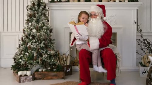 Santa Reads Book to Girl by Christmas Tree
