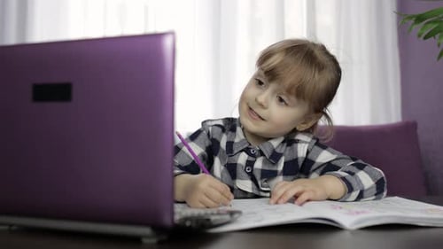 Young Child Writing in Book at Desk Indoors