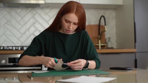 Front View of Pretty Young Woman Cutting Circles Out of Kraft Paper with Scissors for Envelopes