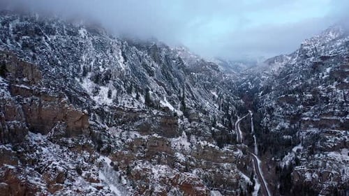 Aerial view of road up through rugged canyon covered in snow