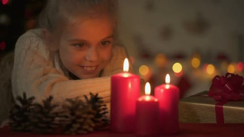 Smiling Child Watches Christmas Candles Glow
