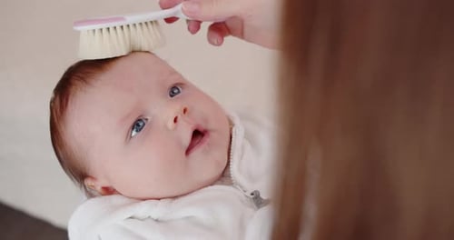 Gentle Mother Brushing Baby's Hair with Love