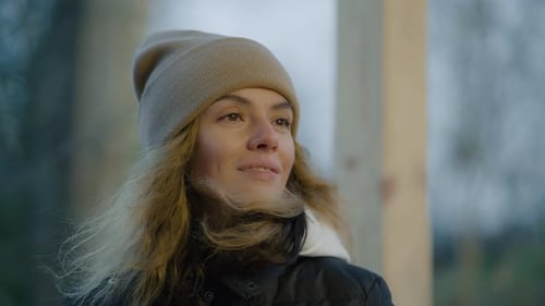 Woman in Winter Hat on Cold Autumn Day Smiles Looks Cheerfully Around