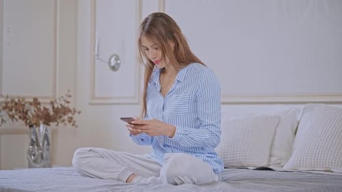 Woman Using Smartphone While Relaxing in Bed