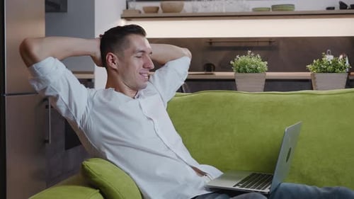 Relaxed Man Using Laptop on Green Sofa