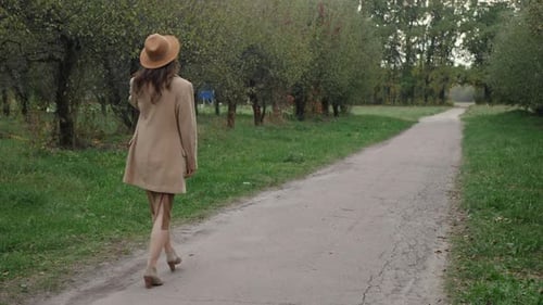 Woman Walks Along Path in Autumn Park
