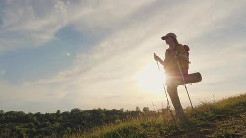 Woman with Trekking Poles Travels in Highlands Sunset