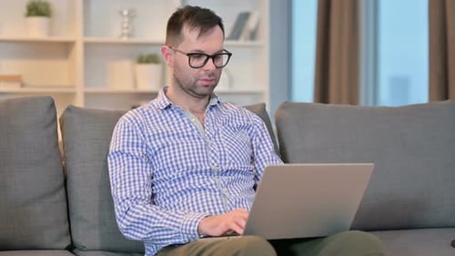 Man Working on Laptop Sitting on Couch at Home